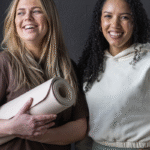 Two young women with a yoga mat.